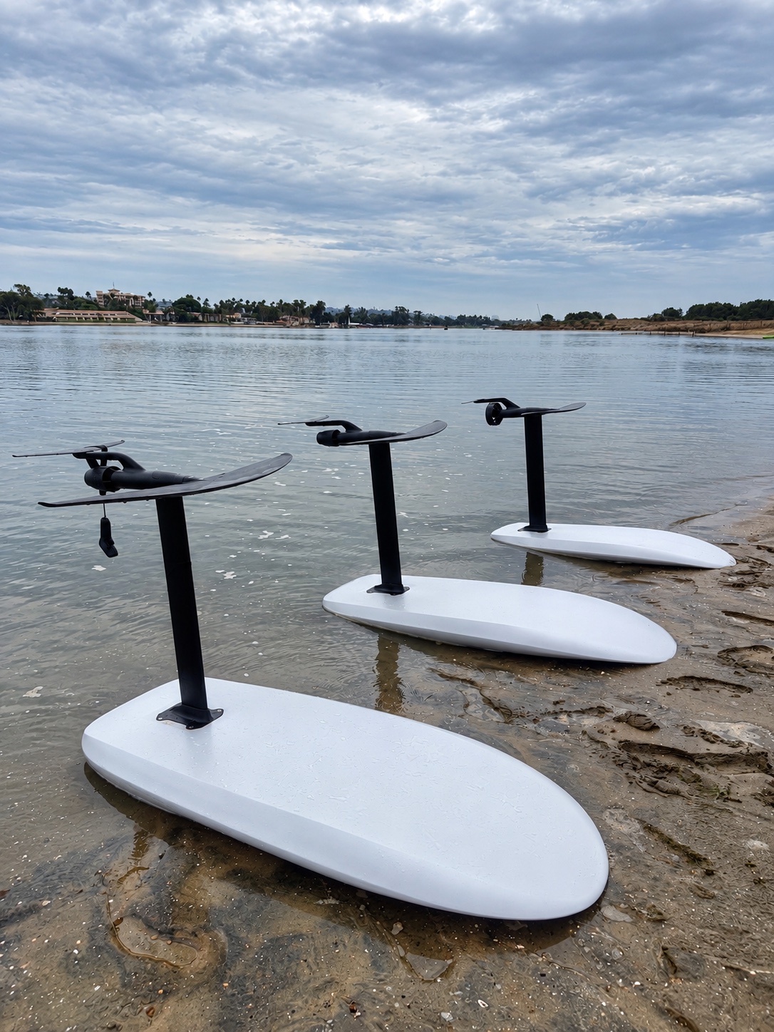 Three eFoil boards lined up at the water’s edge, with their foils visible